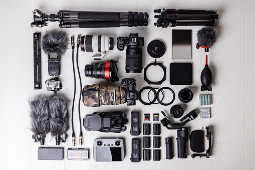 Videography,  photography, sound equipment - top down view of professional drone, camera, lenses, filters, microphone, lighting, cards on white background