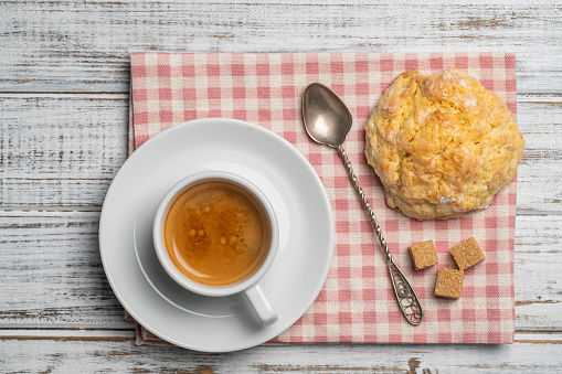 White porcelain coffee cup with saucer and lemon cookies on a wooden table, close up, top view. Hot coffee in a breakfast