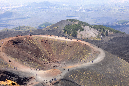 Mount Etna, Sicily, Italy - April 27, 2023: People walking above the Crater Silvestri on the slope of volcano Mount Etna. It is active stratovolcano, tallest and largest volcanic cone in Europe