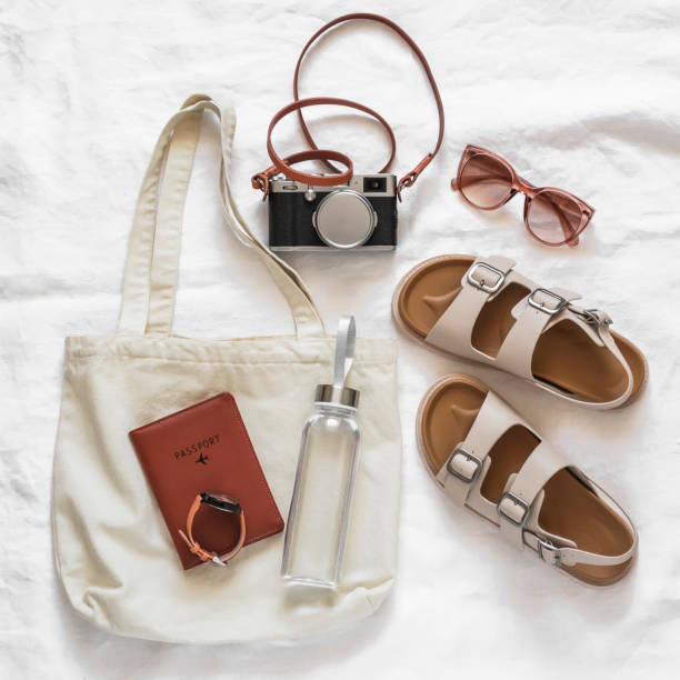 istock Women's accessories for comfortable rest, travel - canvas shopper, camera, comfortable leather sandals, sunglasses, water bottle on a light background, top view 1487898608