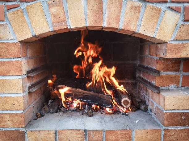 Fireplace with grill and lit fire for roasting food and meat in the garden