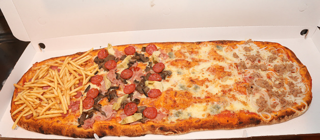 huge long pizza with tomato cheese mozzarella spicy salami mushrooms in takeaway packaging