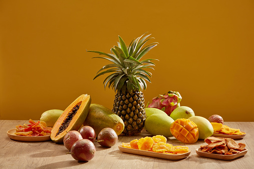 Table with beautiful decorations for Chinese New Year celebration in room is five - fruit tray and jam. Dragon fruit, pineapple, mango, papaya, passion fruit on wooden table. Traditional lunar new year food