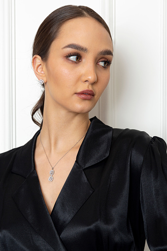 Portrait of a young woman in black clothes on the background of a white interior.