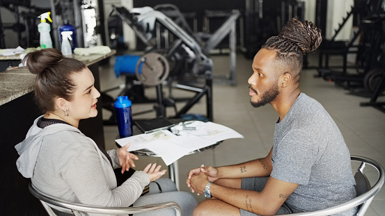 Instructor de fitness discutiendo el programa de entrenamiento con un cliente en el gimnasio photo