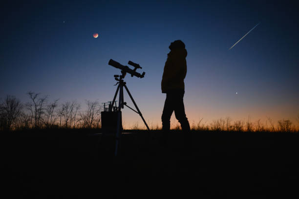 istock Astronomer looking at the starry skies, planets, meteor shower and lunar eclipse with a telescope. 1487914092