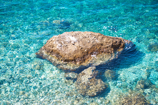 Rock in turquoise sea . Transparent tropical sea water