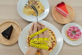 Tape measure around the arms of women. Stop eating trans fats, spaghetti, donuts, waffles and sweets. Lose weight for good health. Top view diet concept