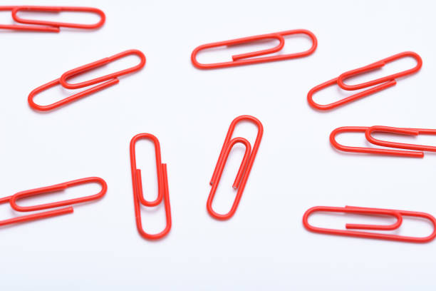 Red paper clips scattered on a white background.  Photographed from above, office wallpaper