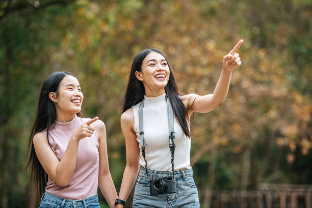 istock Cheerful two asian young women talk and smile while walking in nature park 1487926962