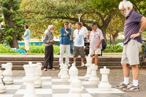 Portrait of a senior man playing chess with his friend in a city square