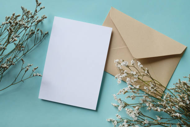 istock White blank greeting or invitation card and envelope with dried plant decoration on violet background. Mock up presentation. 1487928596