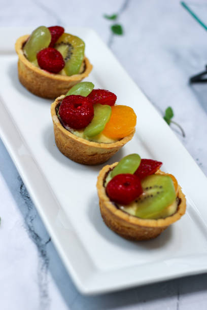 istock fruit pie assorted on white plate . Delicious pastry sweets pies colorful cakes with fresh strawberries, raspberries, grapes, kiwi, fresh peaches and sweet cream. 1487929425