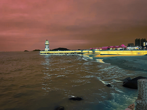 The Zhuhai Beach Lighthouse stands tall against a stunning oceanic backdrop. Located on the southern coast of China, this picturesque landmark has been guiding ships safely to shore for many years. The lighthouse's white and red stripes contrast beautifully against the deep blue sea, making it a popular destination for photographers and tourists alike. Capture the tranquility and beauty of this coastal gem with this stunning photograph.