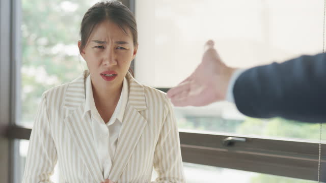 Angry Asian businessman arguing with businesswoman about paperwork failure disputing having conflict confrontation at office. Businesspeople in workplace.