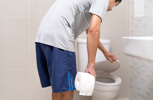 Hombre de pie en el baño sosteniendo pañuelos con dolor de estómago severo. calambres estomacales, dolor abdominal, diarrea, cáncer de colon o vientre photo