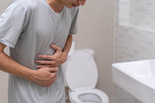 Un hombre de pie tiene diarrea y alimentos severamente tóxicos. Hombre toca vientre en el baño. Dolor abdominal, Diarrea, Concepto de cáncer de colon photo