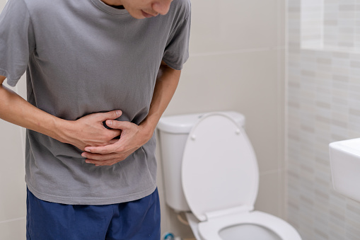 El hombre de pie tiene diarrea y alimentos severamente tóxicos. Hombre toca vientre en el baño. Dolor abdominal, Diarrea, Concepto de cáncer de colon photo