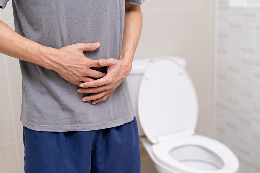 El hombre de pie tiene diarrea y alimentos severamente tóxicos. Hombre toca vientre en el baño. Dolor abdominal, Diarrea, Concepto de cáncer de colon photo