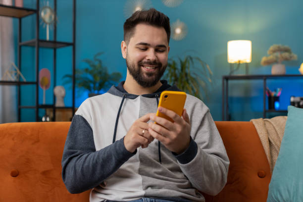 istock Caucasian young man sitting on sofa, using smartphone share messages on social media application 1487944855
