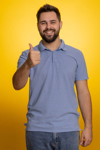istock Happy young man raises thumbs up agrees or gives positive reply recommends advertisement likes good 1487944953