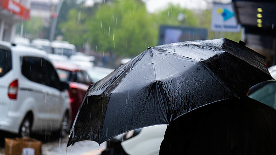 black umbrella wet in the rain. wet and black umbrella man walking down the street