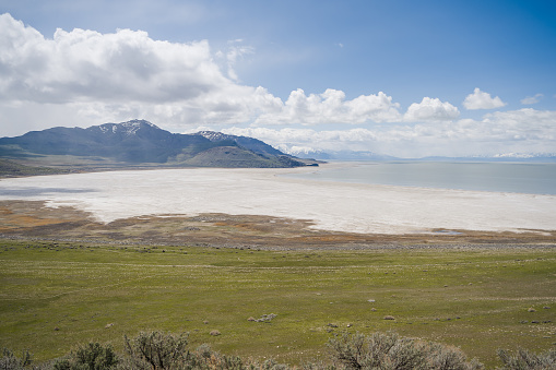 A breathtaking viewpoint on Antelope Island, Utah, showcasing the stunning salt flats, pristine beach, and majestic mountain backdrop that defines this unique landscape.