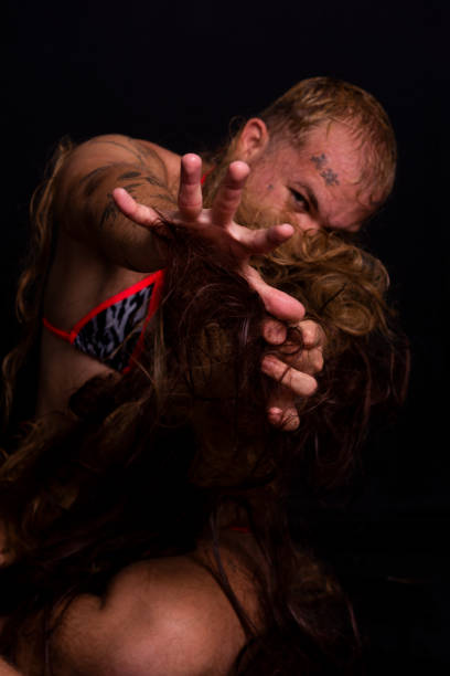 Young actor doing gorilla woman performance. covered in hair. isolated on dark background.