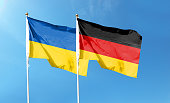 Flags of Germany flag and Ukrainian flag. Waving in blue sky