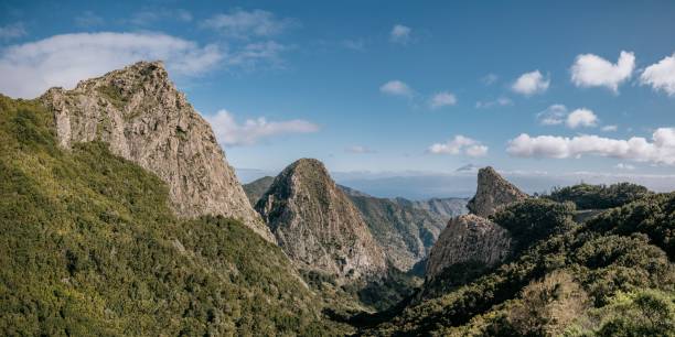 istock Scenic view of a forested mountain range with rolling hills and fluffy clouds in the sky 1487949938
