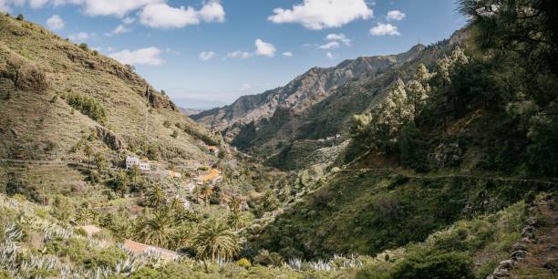 istock Scenic landscape with a valley surrounded by lush green rolling hills dotted with palm trees 1487949966