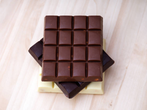 istock Stack of milk chocolate, dark chocolate and white chocolate bars on a wooden background. 1487951775