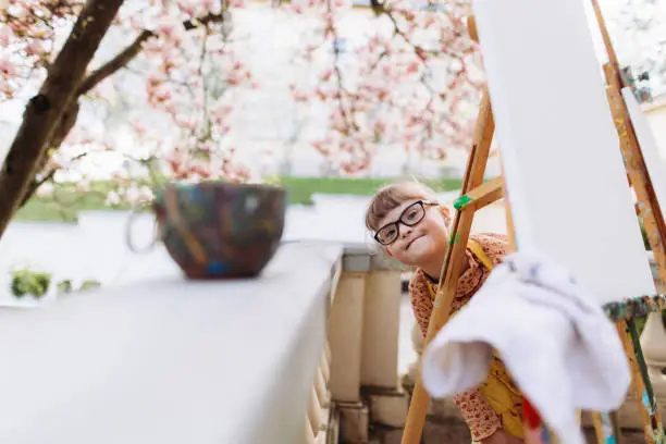 The girl with Down syndrome hiding at the easel in the art-therapy session