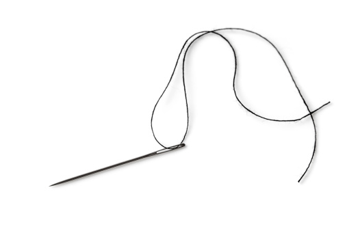 A single needle with black thread on a white background