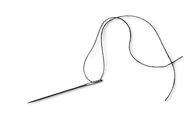 Photo of A single needle with black thread on a white background