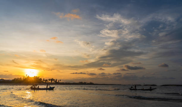 istock Sunset sky clouds over sea in the evening with orange sunlight reflected in water wave and silhouette traditional fishing boat 1487957154