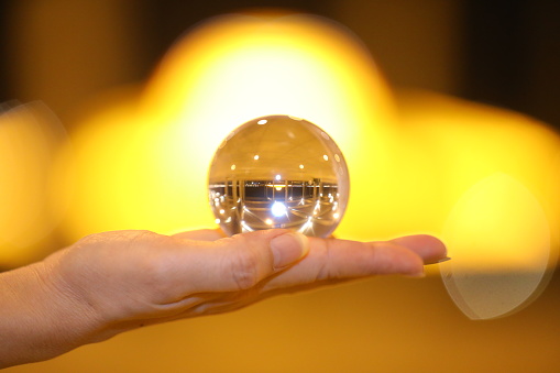 Businessman using crystal ball to predict future at table, closeup. Space for text