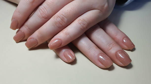istock Acrylic nail extension, manicure, nail correction, hands in the foreground. Reflective design. 1487965898