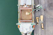 Loading grain into sea cargo vessel in commercial port. Aerial view.