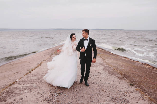 istock Wedding couple walking and hugging near blue sea 1487974207
