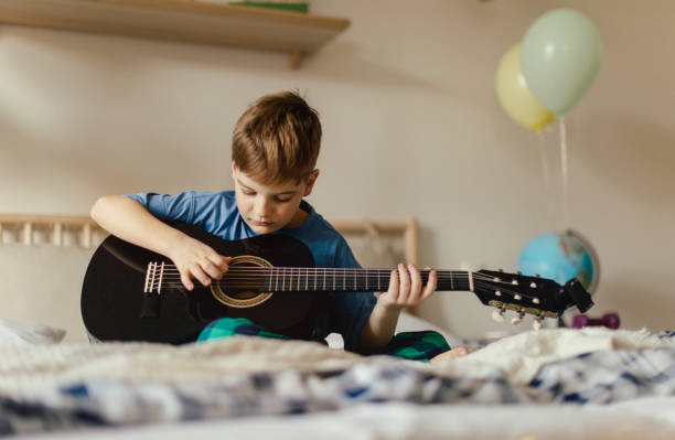 istock Happy boy playing on the guitar in his room. 1487975578
