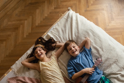 Happy children lying on a bed and having fun together.