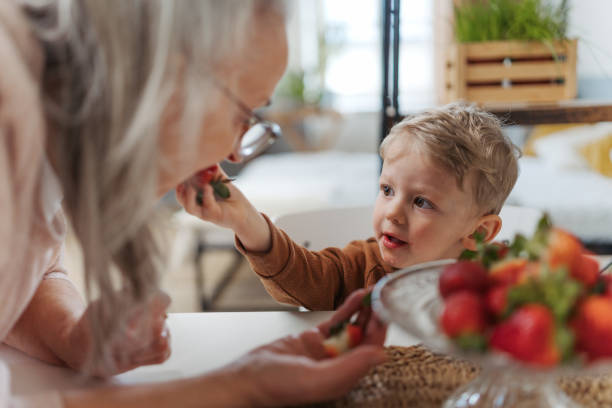 Little boy giving strawberries his elderly grandmother. stock photo