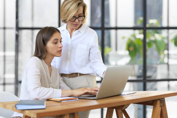istock Two female collegues working with laptop and discussing new project. 1487976683