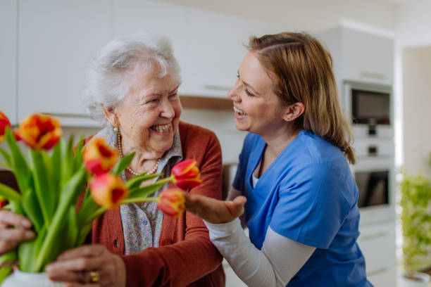 Senior woman and nurse with tulip bouquet. stock photo