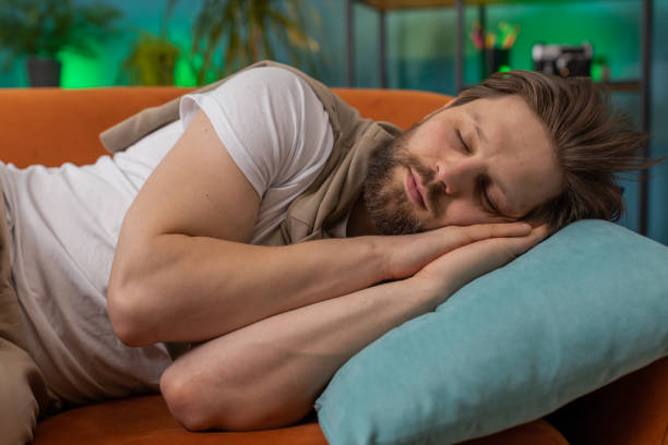 istock Tired young man lying down on comfortable couch, taking a rest, daytime nap relaxing falling asleep 1487976959