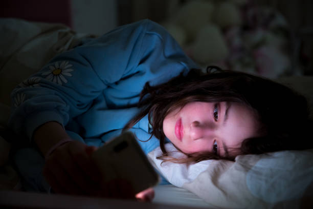 dziecko korzystające ze smartfona leżącego w łóżku - tail fin zdjęcia i obrazy z banku zdjęć