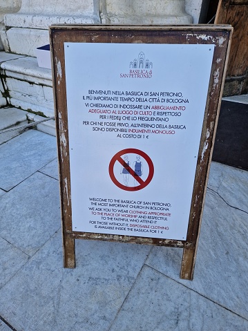 Sign in front of church (Basilica di San Petronio, Bologna, Italy) prescribing appropriate outfit as being mandatory to enter the sacred building - clothing regulations