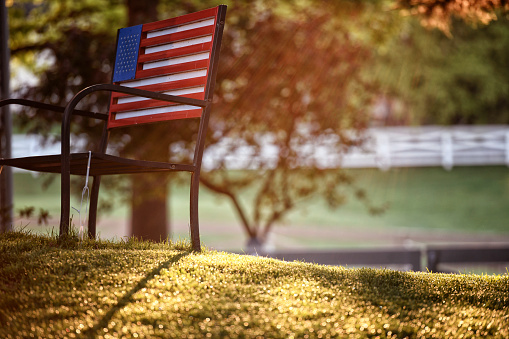 American flag bench in a residential area during sunrise.