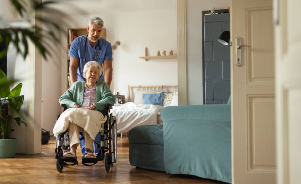 Caregiver doing regular check-up of senior woman in her home. stock photo